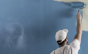 Painter using roller to paint striking blue on London apartment wall